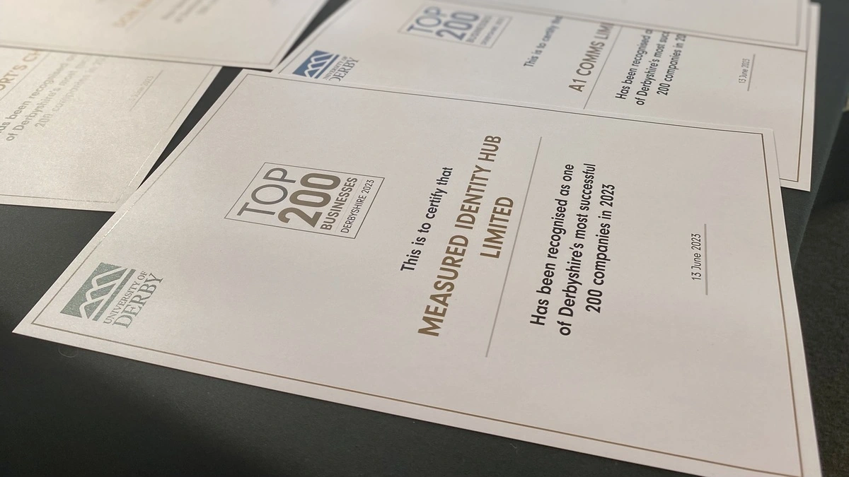 Close up image of Mi Hub's Top 200 Certificate on a table alongside other certificates 