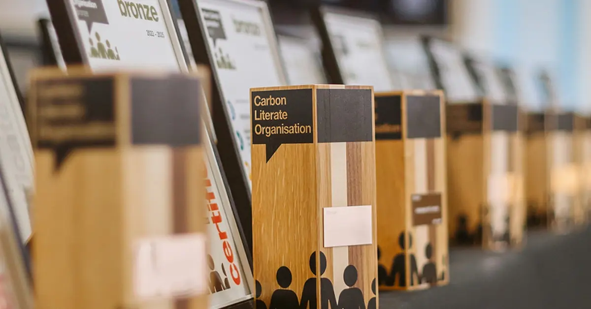 A row of polished wooden awards and framed certificates displayed neatly on a table. in front of 